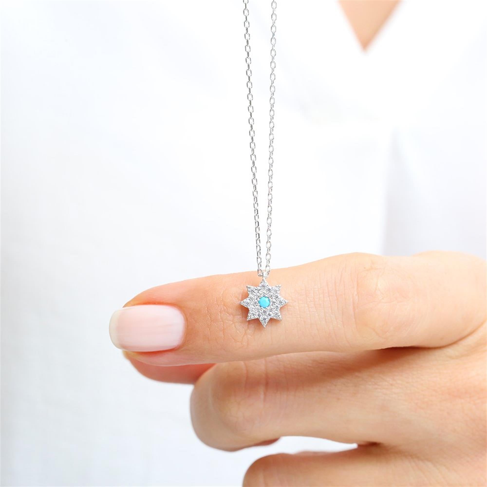 Radiant sterling silver starburst necklace with turquoise center and pavé zirconia – inspired by cosmic elegance.