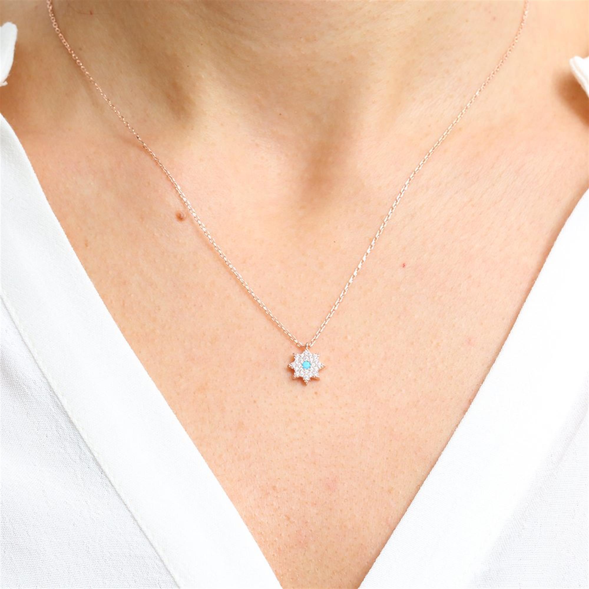 Radiant rose gold starburst necklace with turquoise center and pavé zirconia – inspired by cosmic elegance.