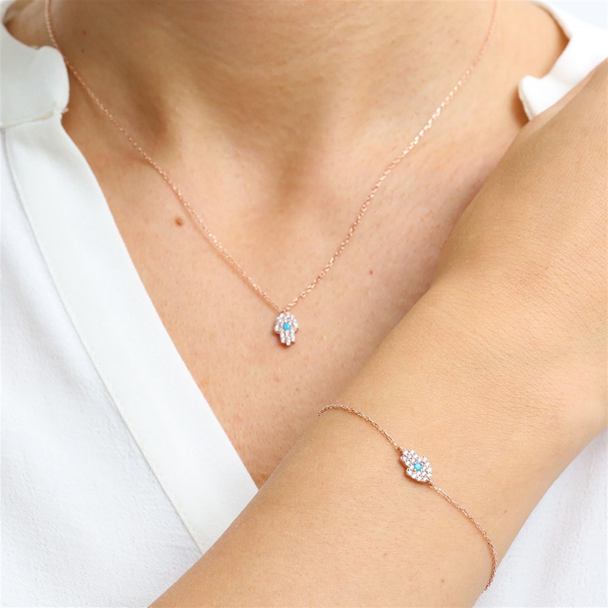 A rose gold-plated 925 silver jewelry set featuring a turquoise-accented Hamsa hand on both a delicate necklace and bracelet.