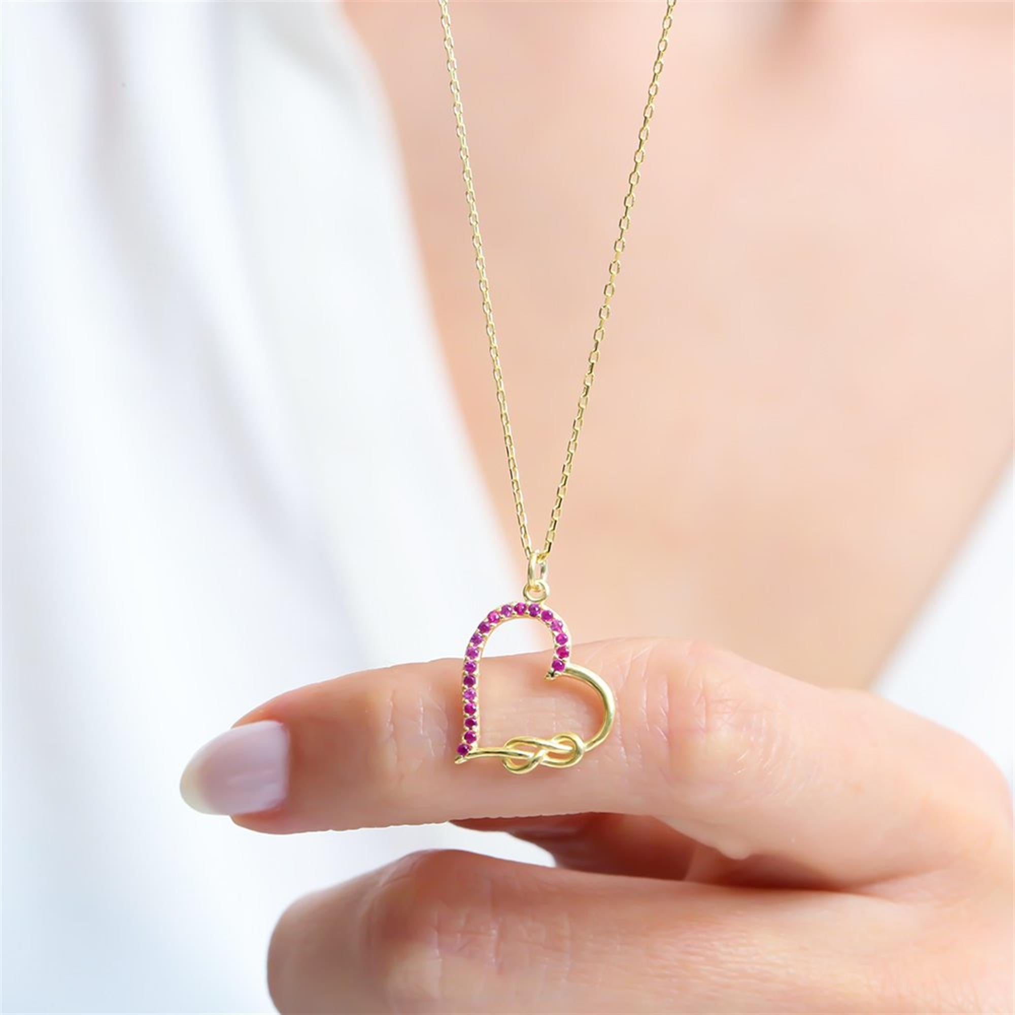 Elegant gold-plated heart necklace with sparkling fuchsia stones and infinity symbol, representing eternal love and passion.