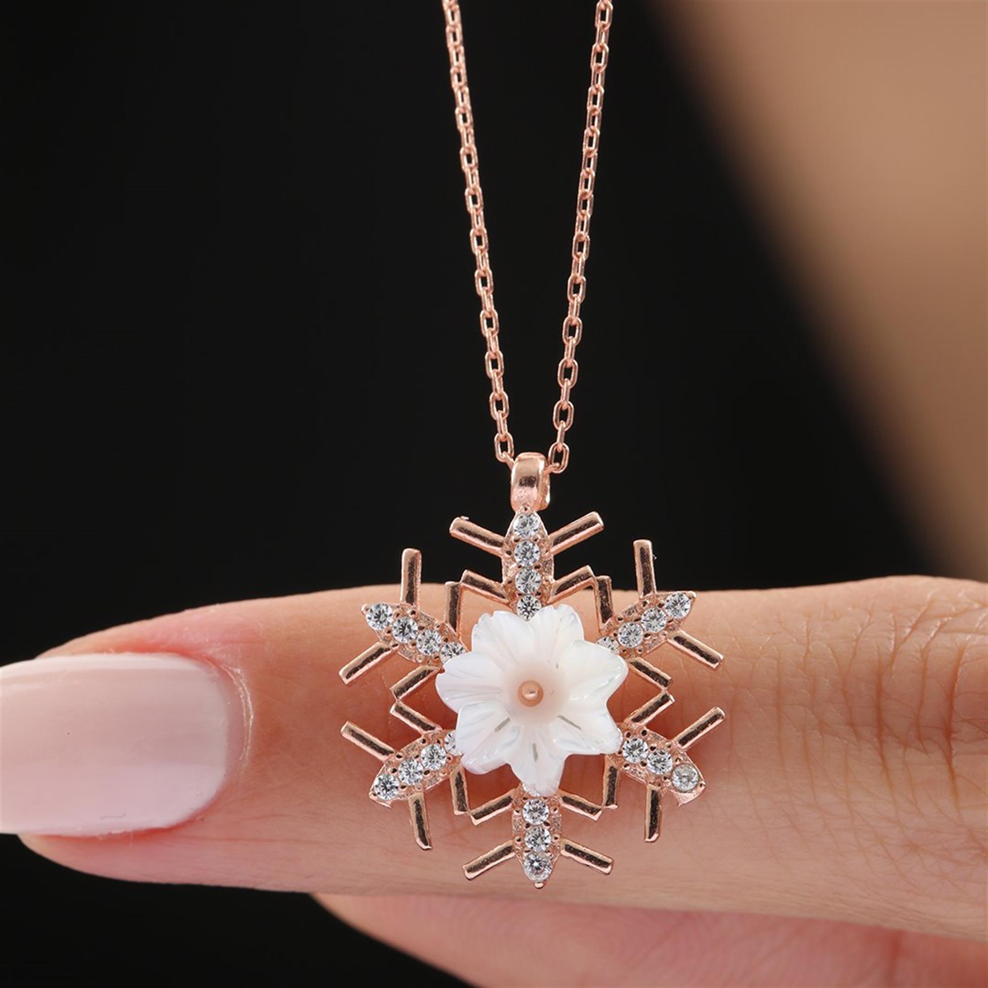Rose gold snowflake necklace with a carved white magnolia flower and sparkling CZ – a delicate winter bloom in fine jewelry.