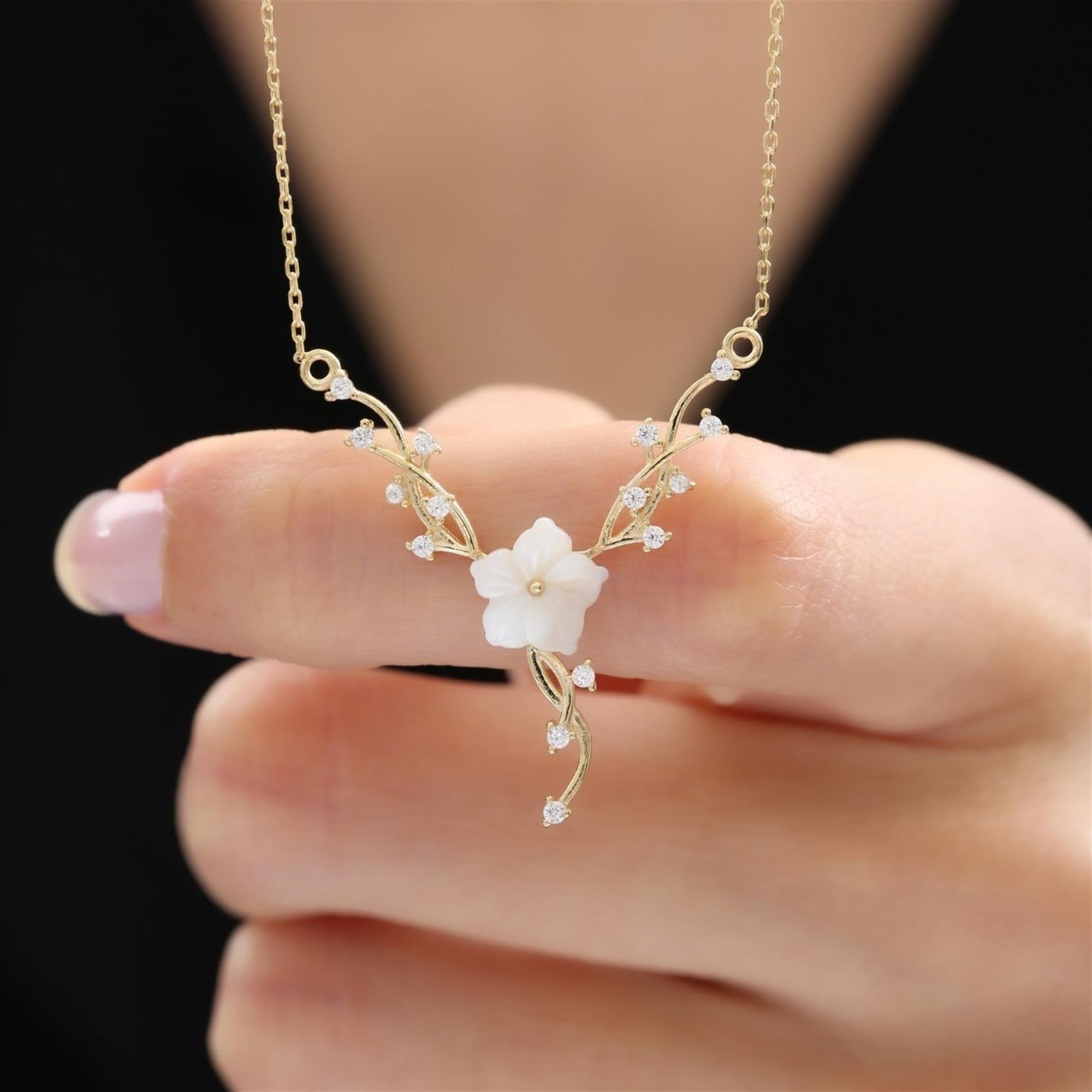 Gold necklace with white magnolia flower and sparkling vine details with cubic zirconia