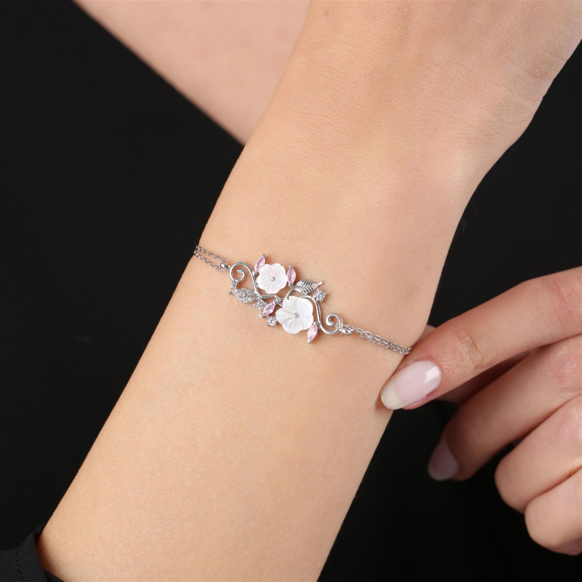 Pulsera en oro rosa con flores de magnolia blancas y dijes de hojas de circonitas – diseño floral elegante para mujer