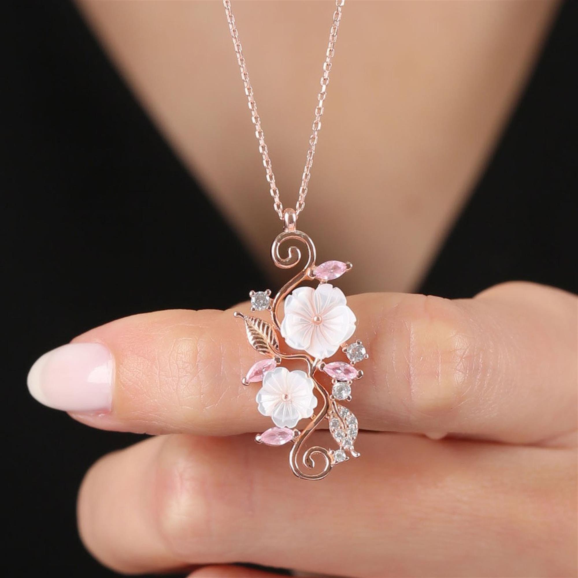Rose gold pendant with two white magnolia flowers, pink gemstones and vine-like floral details