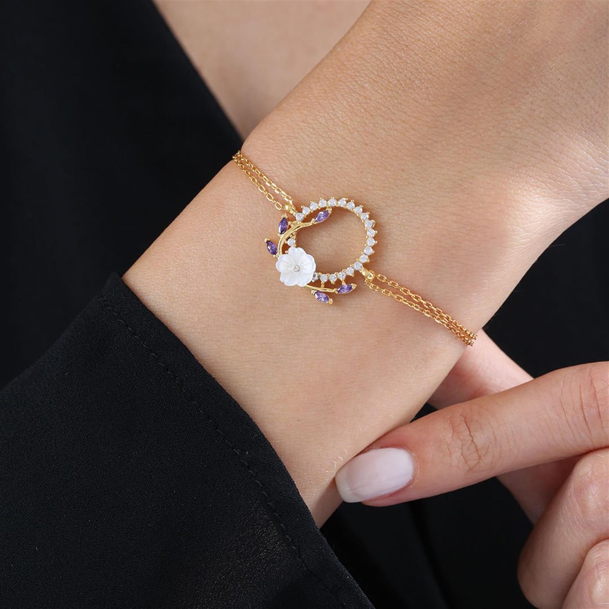 Goldenes Armband mit rundem Design, weißer Blume und amethystfarbenen Steinen