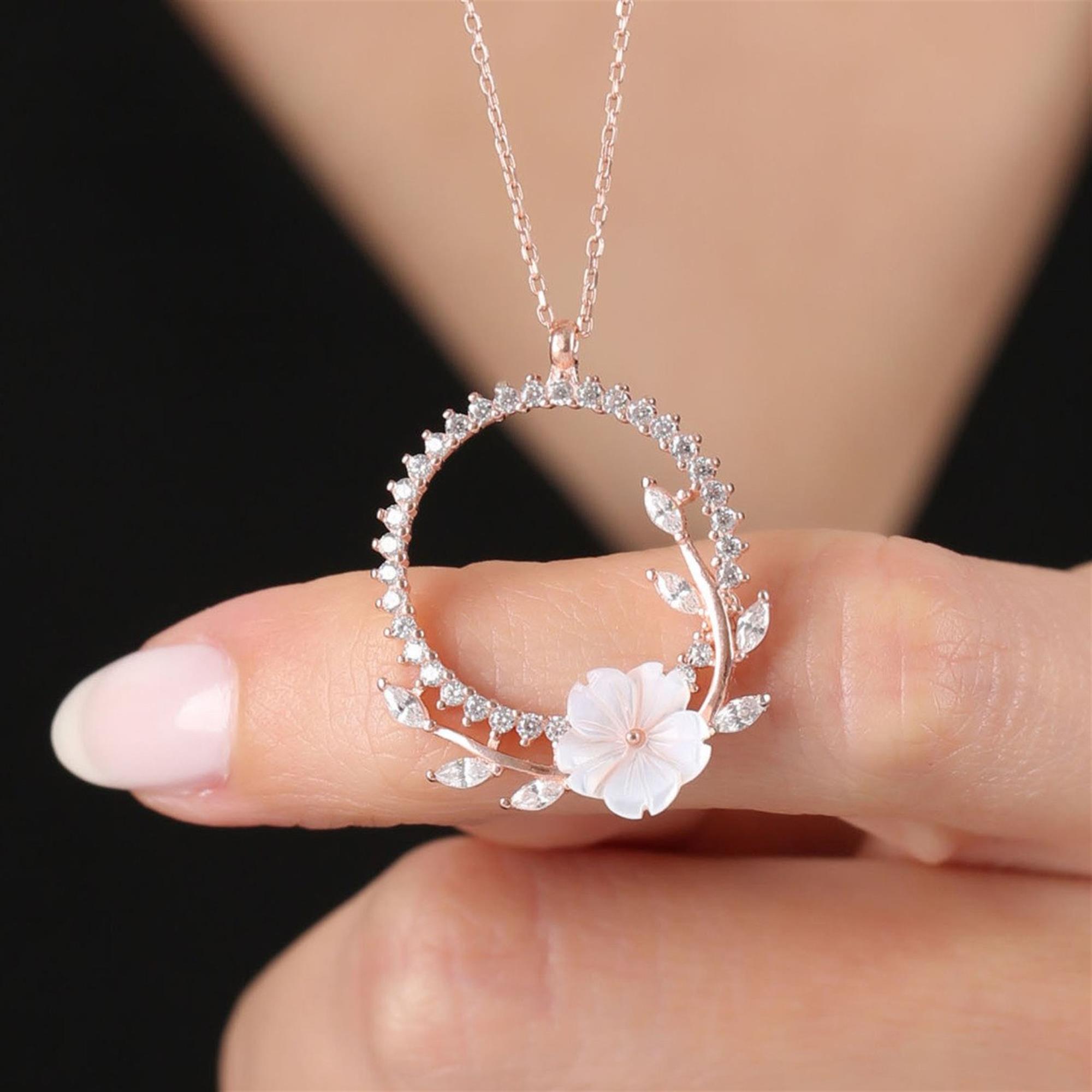 Rose gold circle necklace with white flower and sparkling leaf accents