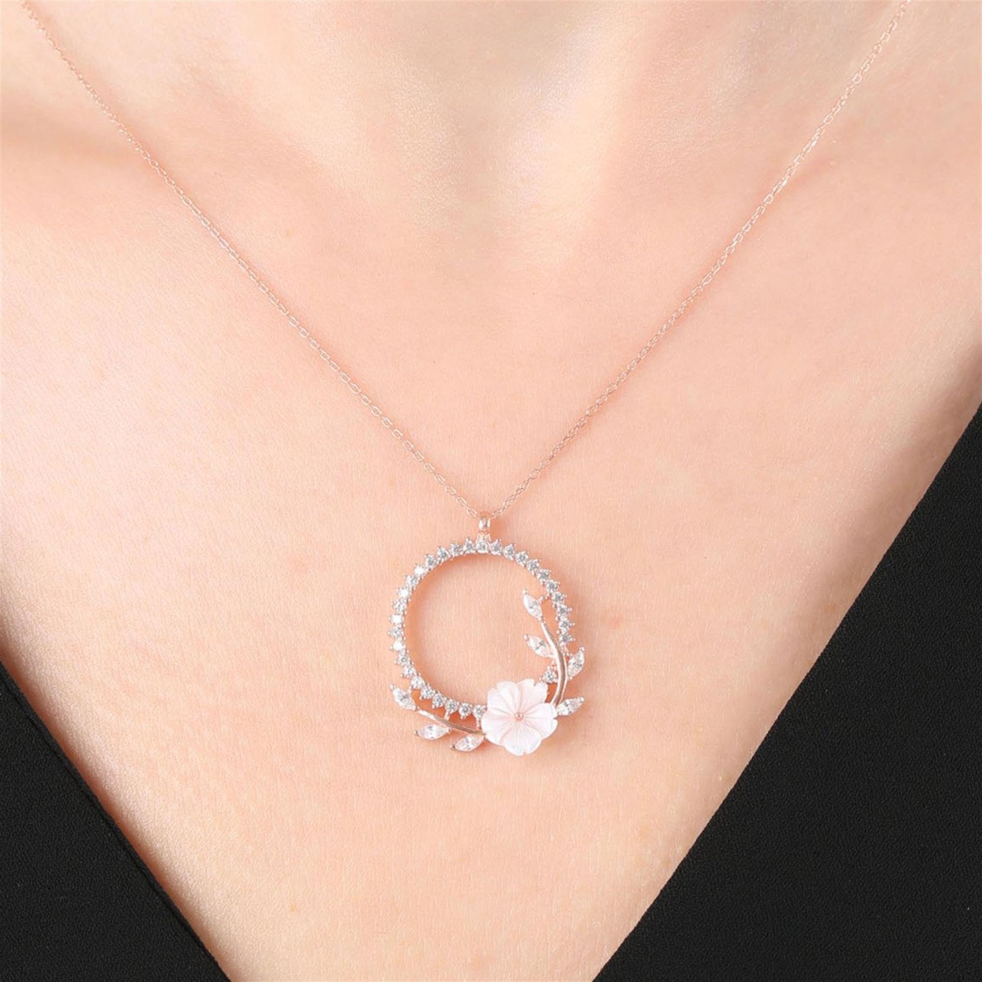 Collar circular rosa con flor blanca y detalles de hojas brillantes