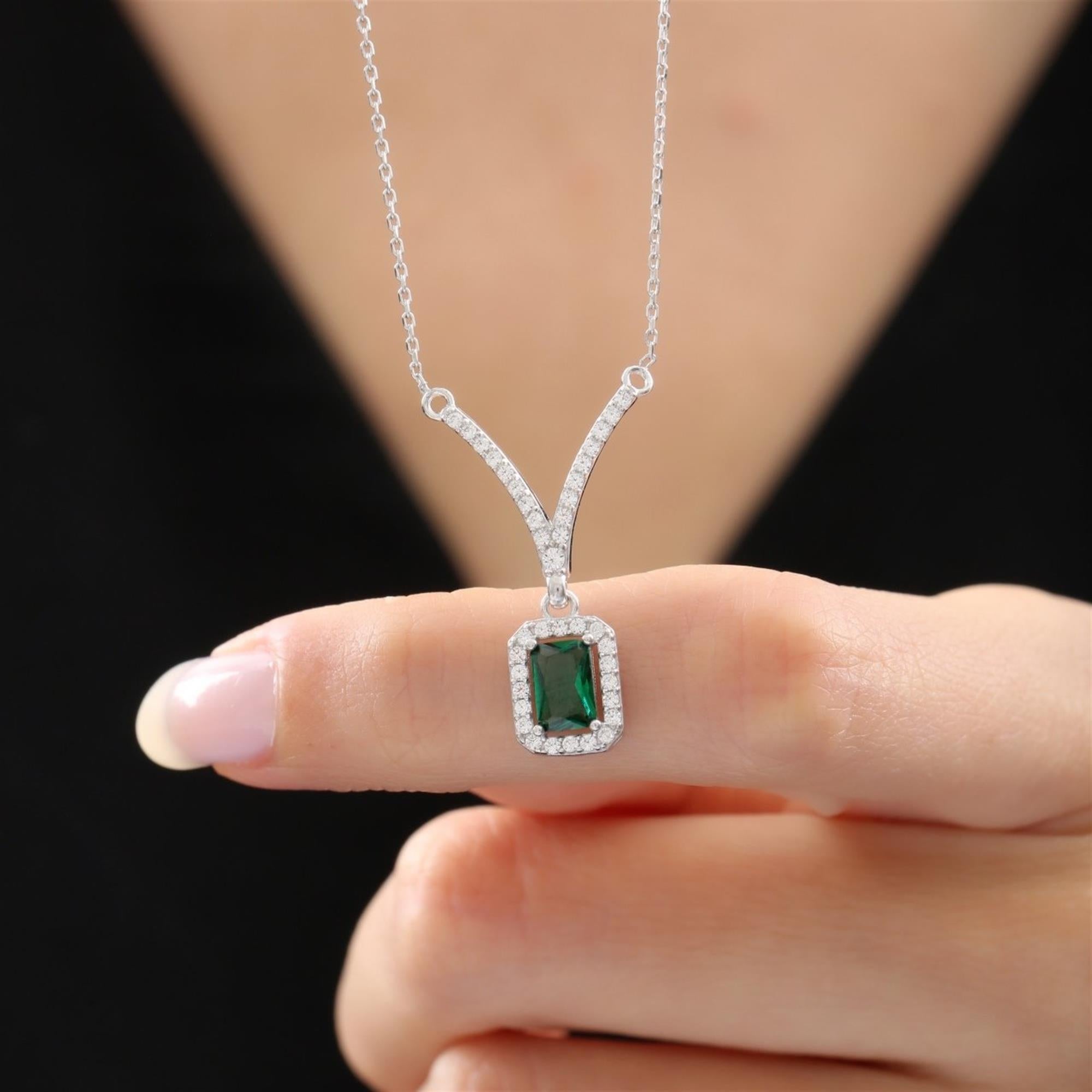 Silver necklace with emerald green rectangular stone and zirconia halo on a V-shaped connector