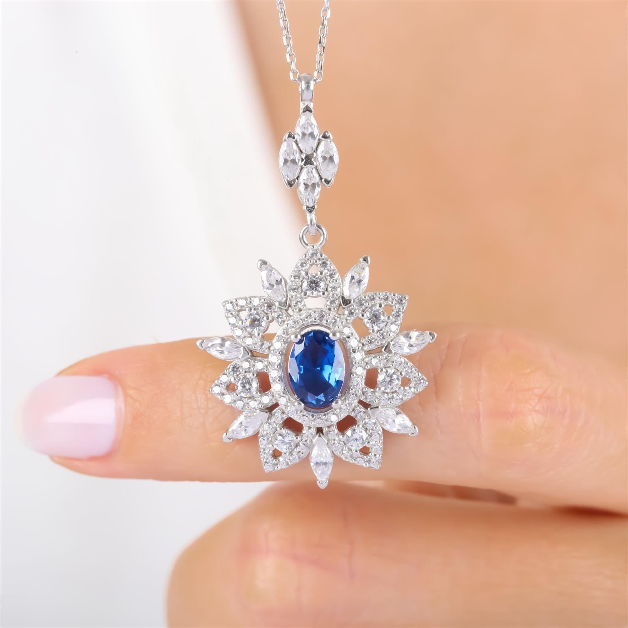 Sterling silver royal pendant necklace with oval-cut sapphire and floral CZ halo