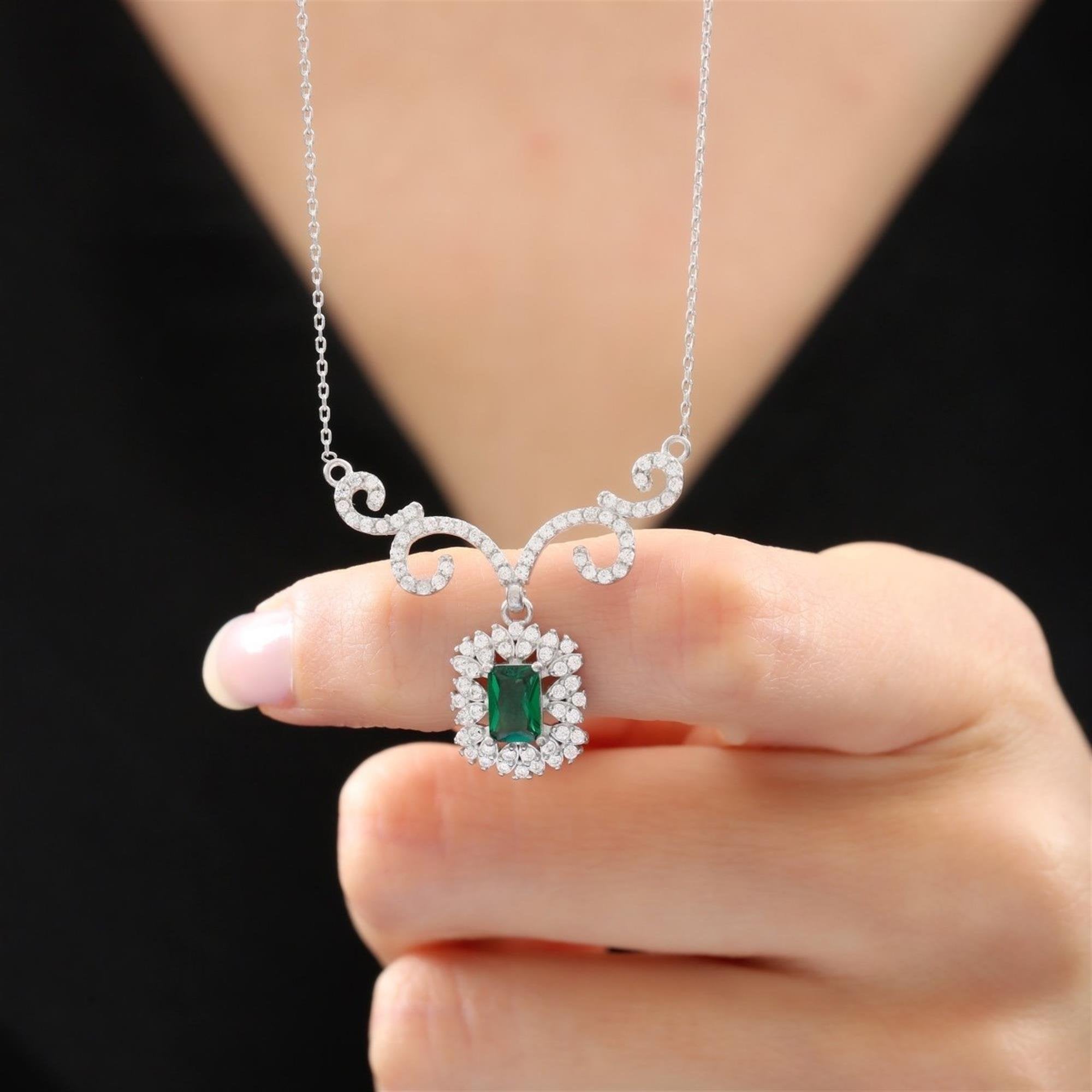 Elegant silver necklace with oval emerald CZ and halo stones, featuring vintage-style swirling accents – perfect for regal looks
