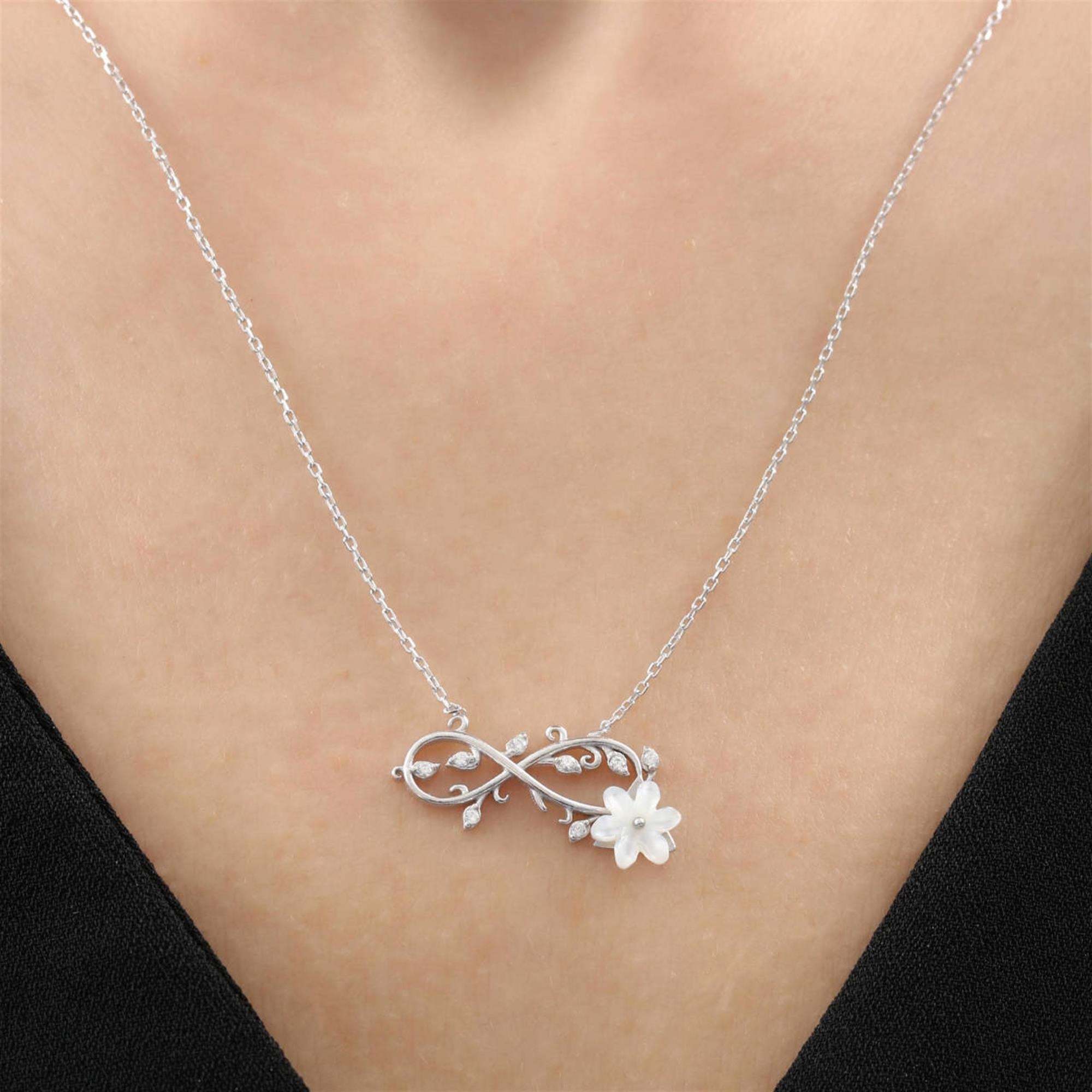 Silberne Unendlichkeitskette mit weißer Magnolienblume und glitzernden Blättern