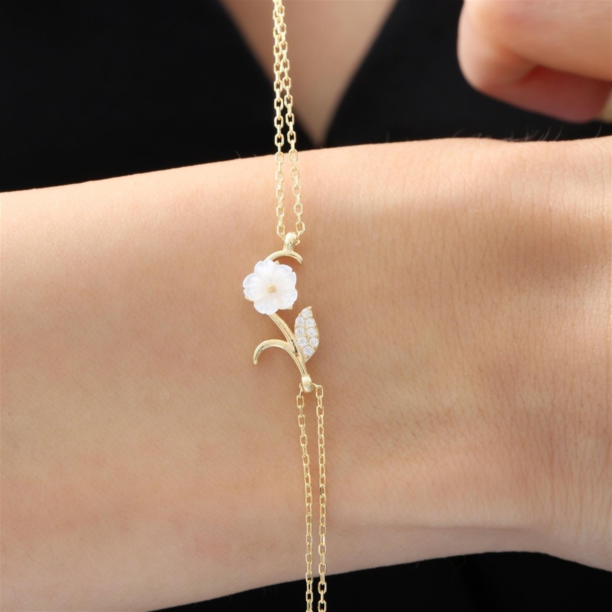 Elegant gold-tone bracelet with a mother-of-pearl magnolia flower and cubic zirconia leaf – feminine nature-inspired wristwear