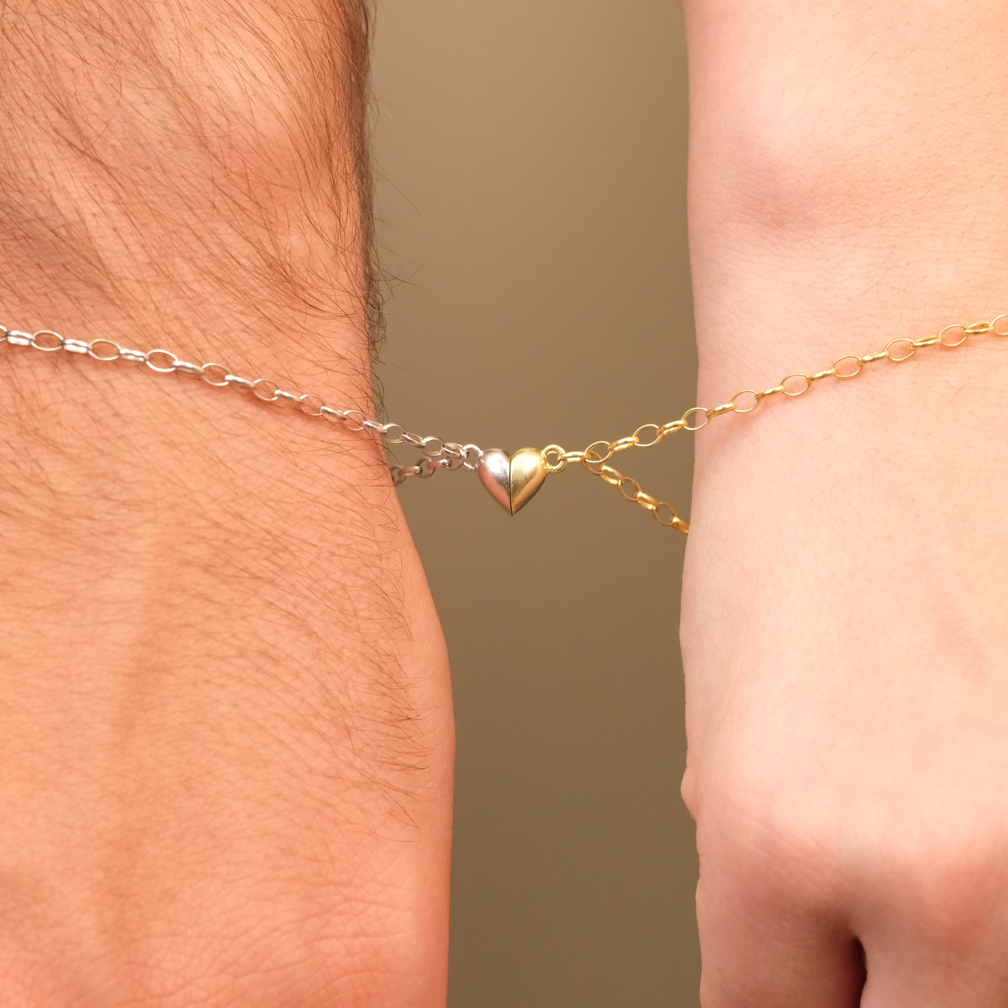 Two anklets on a person's ankle, one gold and one silver, with a heart-shaped charm.