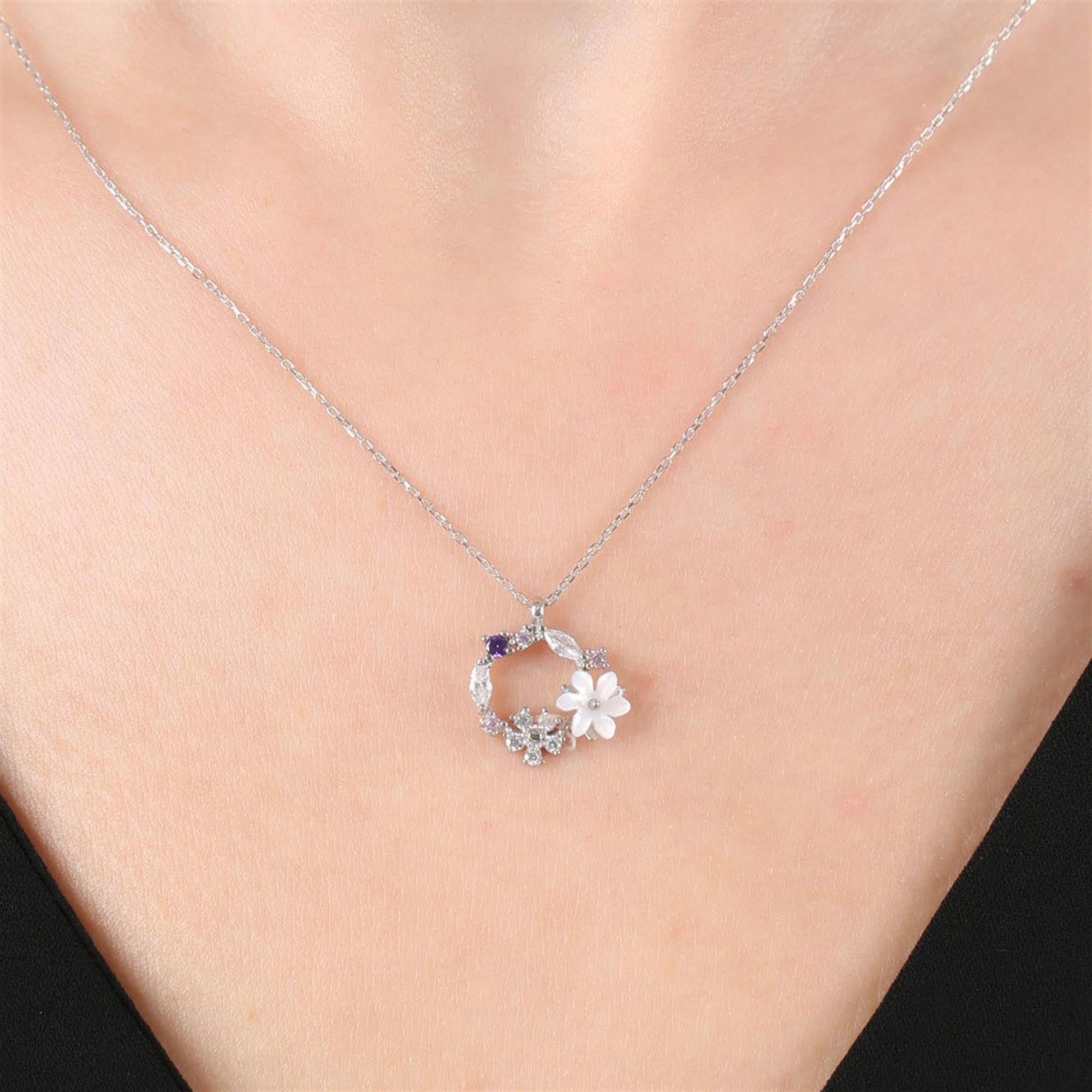 Collar circular plateado con flor de magnolia blanca y detalles florales brillantes