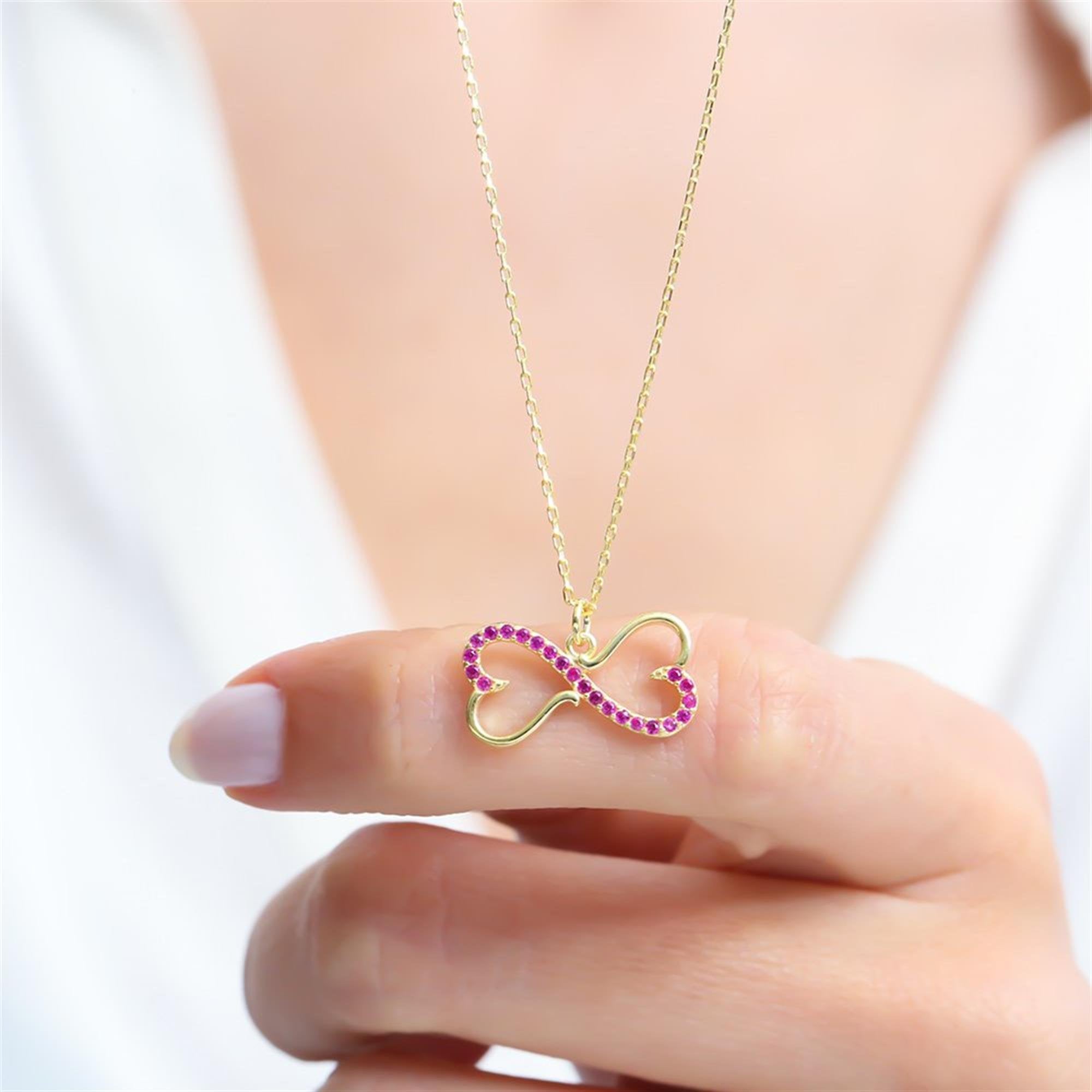 Gold infinity and heart necklace with fuchsia stones a symbol of eternal love and emotional connection.