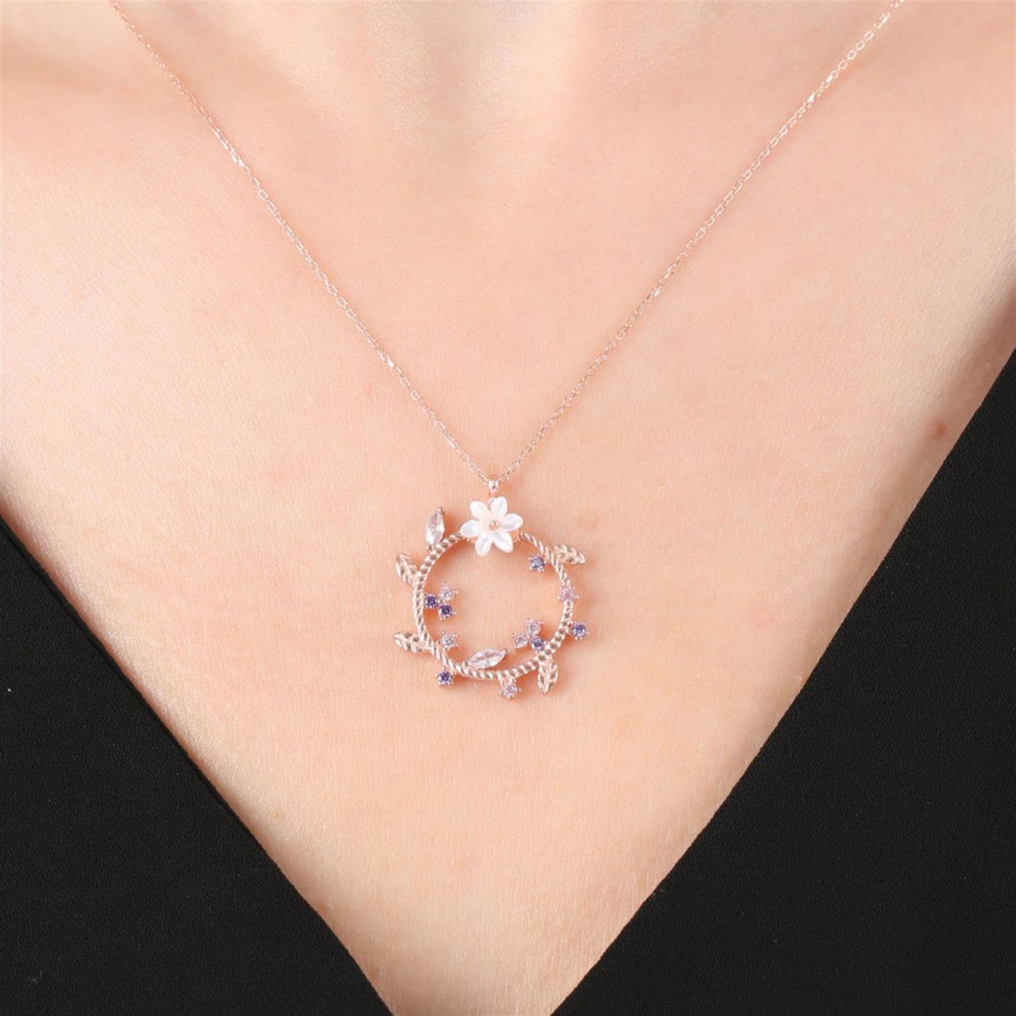 Collar circular rosa trenzado con flor de magnolia blanca y detalles de piedras moradas y rosas