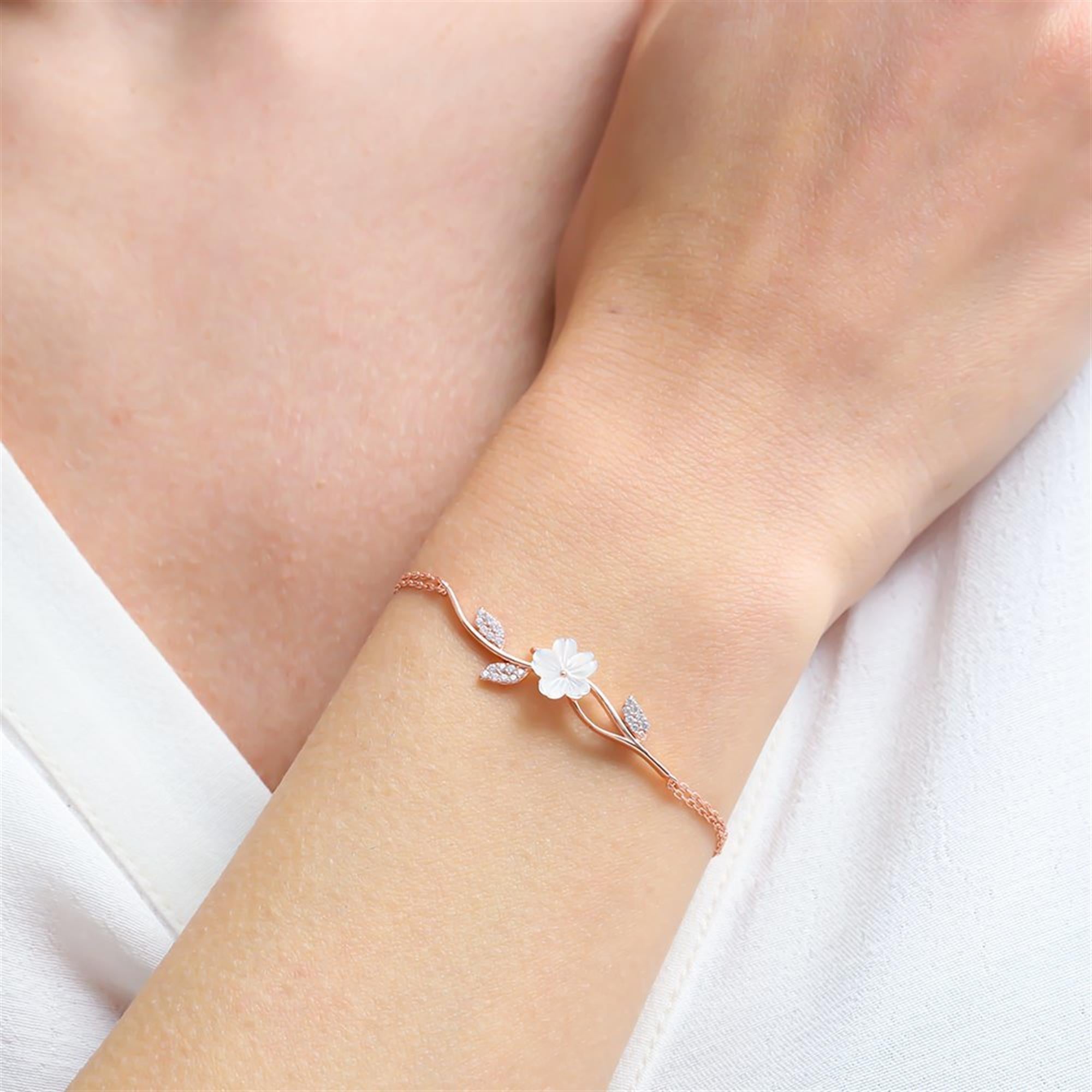 Rose gold magnolia branch bracelet with white blossom and zircon leaves – romantic spring accessory for daily elegance.