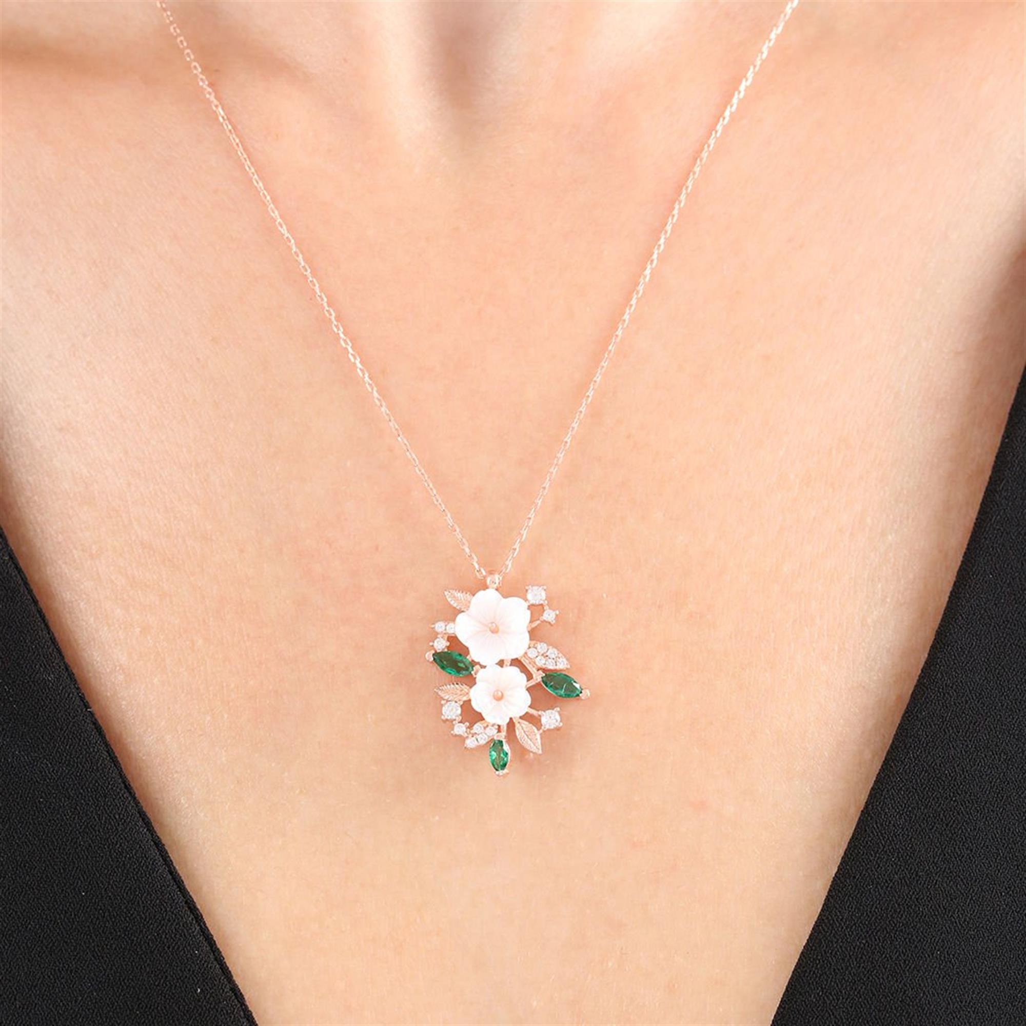 Rose gold necklace with white magnolia flowers, emerald green leaves and sparkling crystals