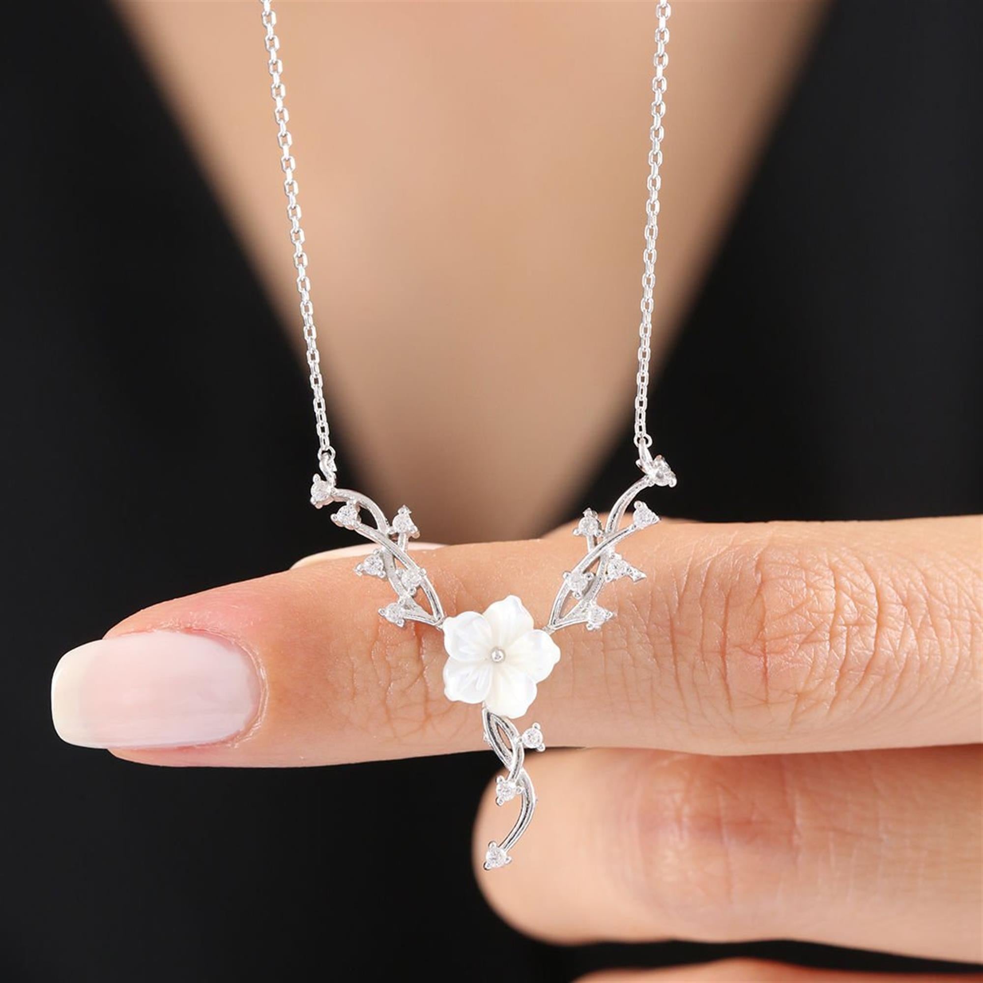 Sterling silver necklace with white magnolia flower and vine-inspired sparkling leaf design