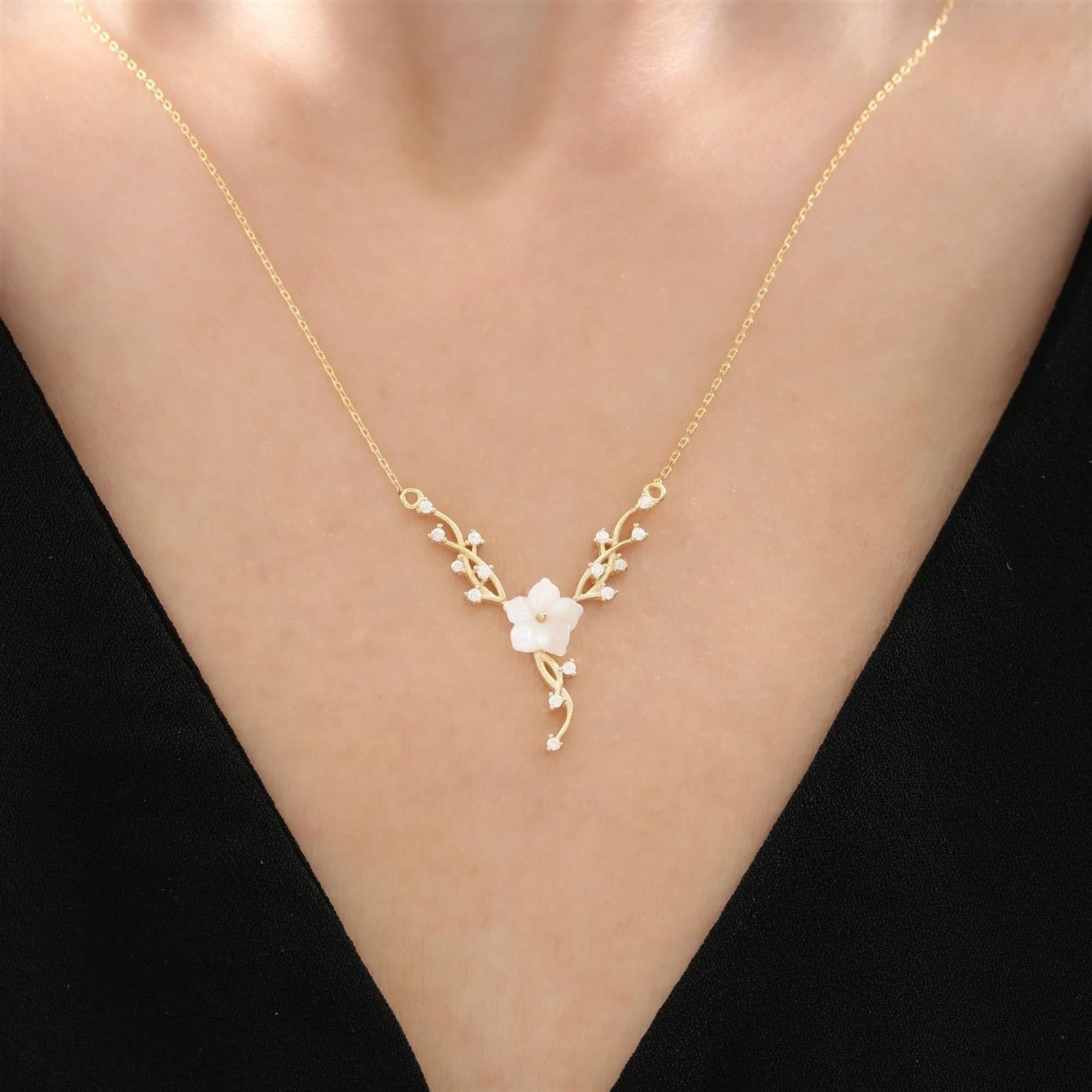 Collar dorado con flor de magnolia blanca y detalles de enredadera brillante