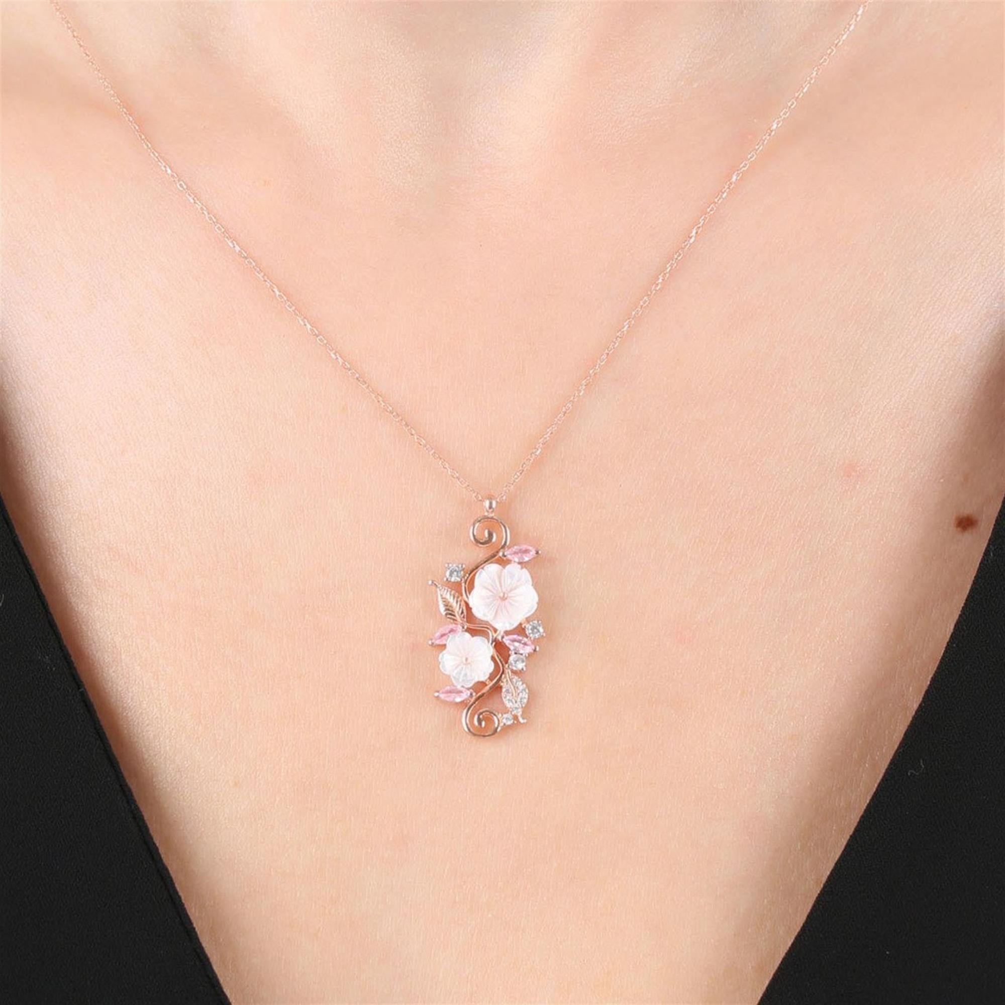 Colgante rosa con dos flores de magnolia blancas, piedras rosas y detalles florales enredados