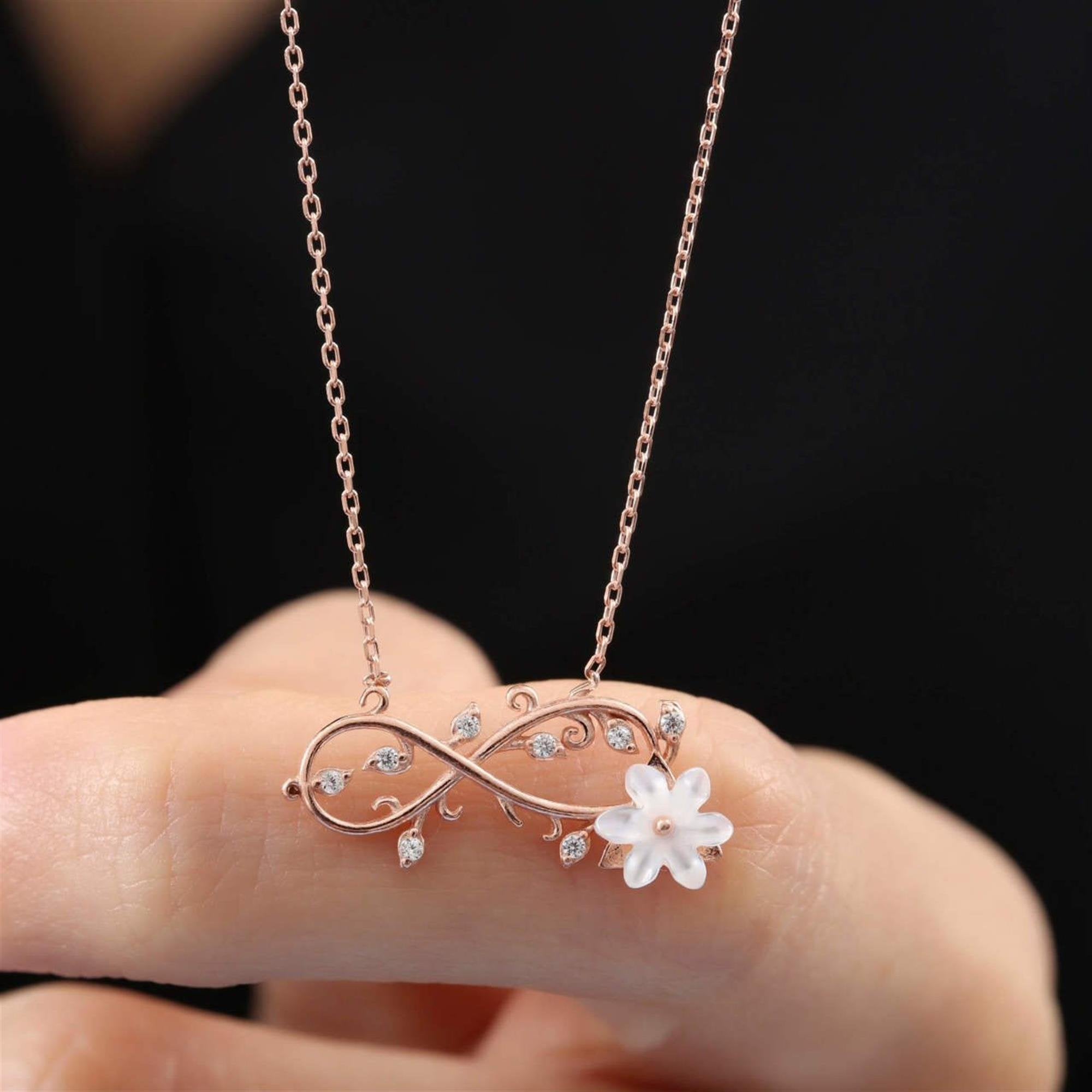 Collar de infinito en tono rosa con hojas de circonita y flor de magnolia blanca – joya inspirada en la naturaleza